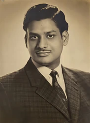 Sepia portrait of Ajay Rungta as a young man, wearing a suit and tie, with a neat hairstyle and mustache, looking directly at the camera.