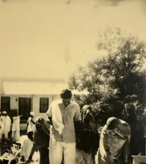 Sepia photo: young Ajay Rungta in Chaibasa. Central figure, blurred background with people and building.