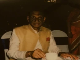 Portrait of Ajay Rungta (Dadu) around age 75, seated and holding a teacup, wearing a vest and white shirt.
